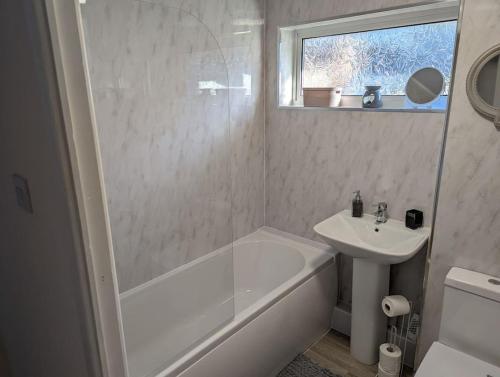 a bathroom with a white tub and a sink at THE KILSYTH,detached bungalow Warrington in Warrington