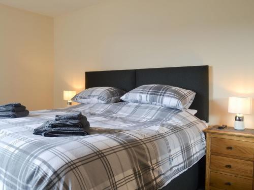 a bed with a plaid blanket and pillows on it at Aurora in Lossiemouth