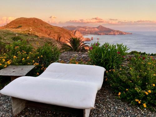 ein weißer Stuhl auf einem Hügel mit dem Meer in der Unterkunft Case Quattrocchi in Lipari