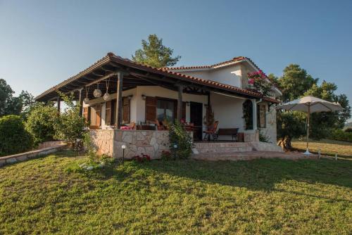 a small house with an umbrella in a yard at Spectacular villa near the beach! in Agia Paraskevi