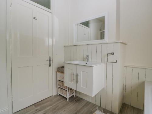a white bathroom with a sink and a mirror at Primrose Cottage in Cheltenham