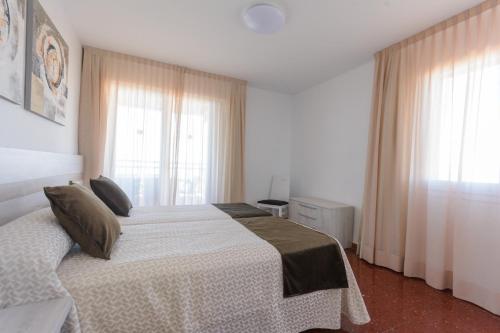a bedroom with a bed and two windows at Beach Family Apartments in Salou