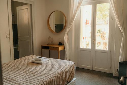 a bedroom with a bed and a mirror and a window at Hôtel Le Cro-Magnon in Les Eyzies-de-Tayac