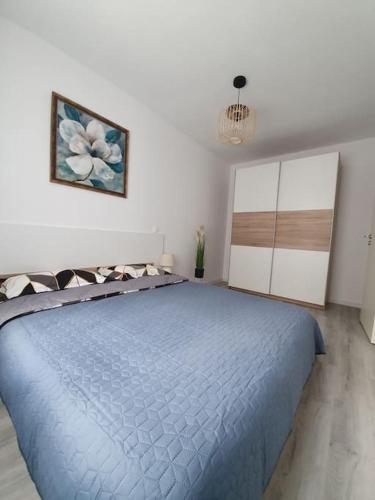 una camera con un letto blu e un dipinto sul muro di Apartament AMA Sibiu a Sibiu