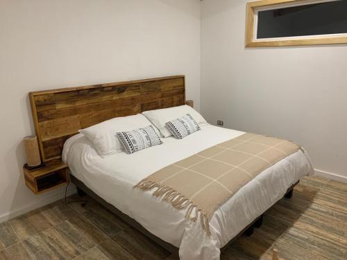 um quarto com uma cama grande e uma cabeceira em madeira em Cabañas El jardín de Jacinta em Coihaique