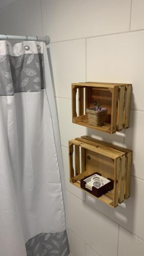 a bathroom with a wooden shelf and a shower curtain at Cabañas El jardín de Jacinta in Coihaique