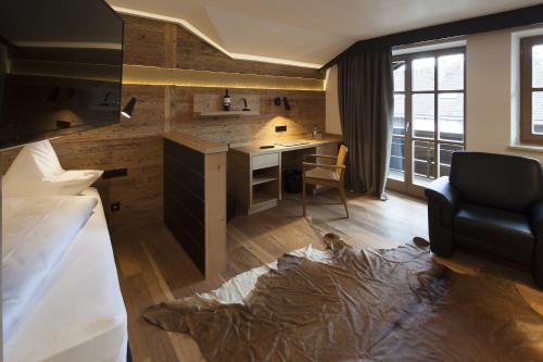 a room with a bed and a desk with a chair at Boutique Hotel Gams in Oberstdorf