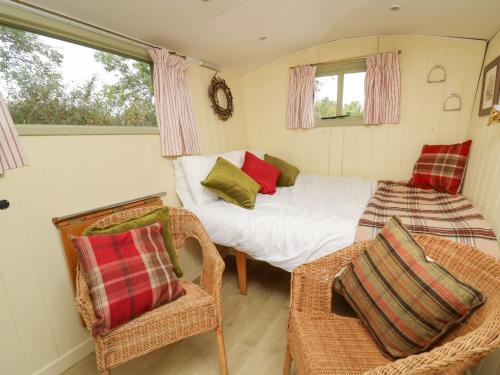 ブレコンにあるTilly Gypsy-style Caravan Hutのベッドと椅子付きの小さな部屋です。