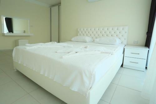 a white bed with two white towels on it at Orka Royal Hills Apartments in Oludeniz