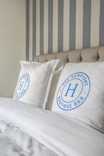 a bed with two pillows on top of it at The Hamptons Boutique Hotel in Ghent