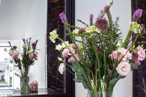 two vases filled with flowers in front of a mirror at The Hamptons Boutique Hotel in Ghent