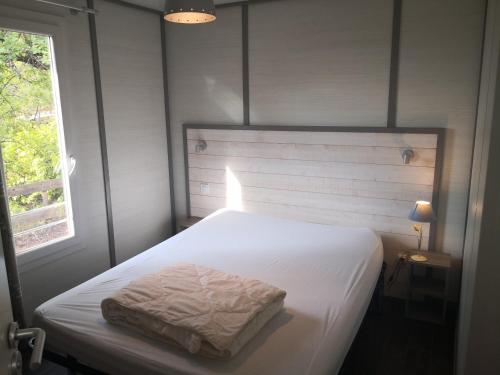 a bedroom with a white bed and a window at La Colline des Ocres Village de vacances 3 étoiles in Apt