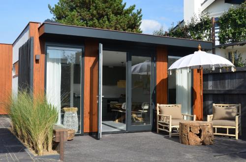 a modern house with glass doors and an umbrella at Olive Beach, luxury beachhouse 150 m from the beach in Noordwijk aan Zee