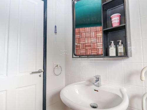 a white bathroom with a sink and a mirror at Coastguard Cottage in Rye