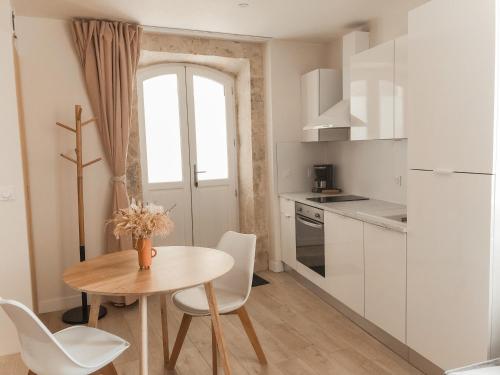 una pequeña cocina con mesa de madera y armarios blancos en Le Seize - Studio dans le centre historique d'Auch, en Auch