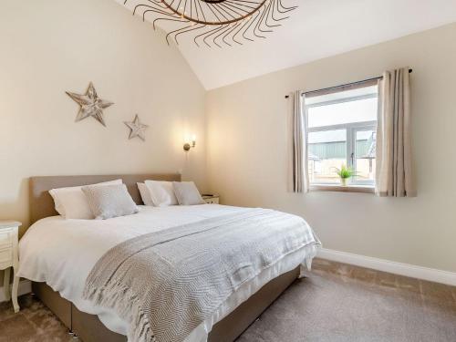 a white bedroom with a bed and a window at Dip Tub Den - Uk35989 in Wansford