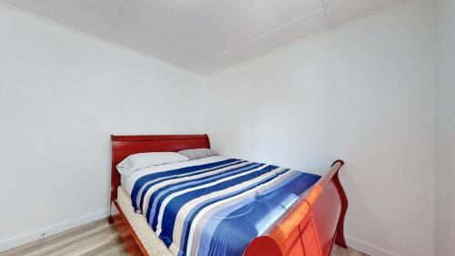 a bed in a white room with a striped blanket at Main Beach River Retreat - Wasaga Beach 1 - Main Strip - 93 Mosley St in Wasaga Beach