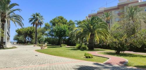 un camino en un parque con palmeras y un edificio en Sunnybeach Apartment mit direktem Strandzugang, en Denia