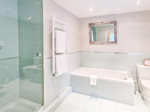 a white bathroom with a tub and a shower at Blashford Manor Farm House in Ellingham