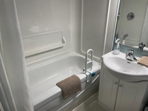 y baño blanco con lavabo y bañera. en Rivers End Motel, en Corner Brook
