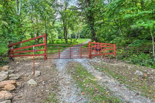 a red gate on a dirt road with trees at Turkey Hollow Cabin with Stunning Open Views! in Clyde