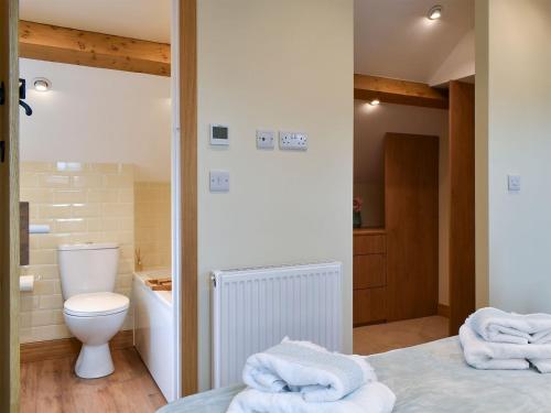 a bathroom with a toilet and towels on a bed at The Old Pump House - Uk34451 in Child Okeford