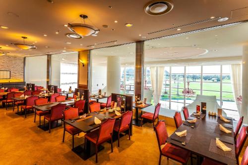 a restaurant with tables and chairs and windows at ANA Holiday Inn Resort Miyazaki by IHG in Miyazaki