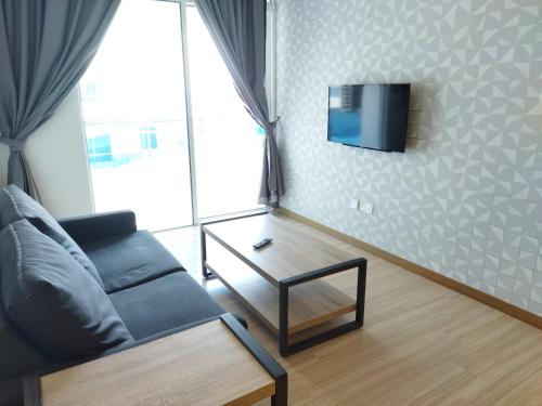 a living room with a couch and a tv on the wall at ExcluSuites Malacca @ The Wave Residence in Melaka