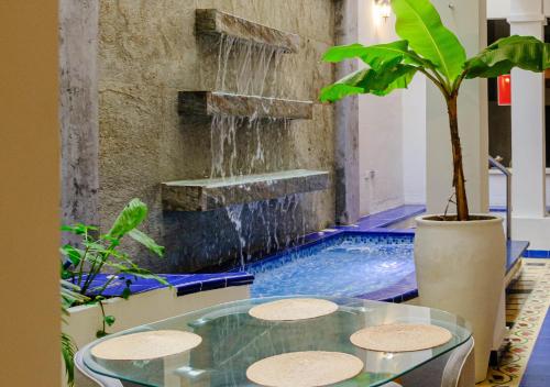 a swimming pool with a fountain and a glass table at Casa Rosa - Alma Hotels in Santa Marta