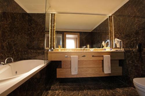 ein Badezimmer mit einer Badewanne, einem Waschbecken und einem Spiegel in der Unterkunft WOW Istanbul Hotel in Istanbul
