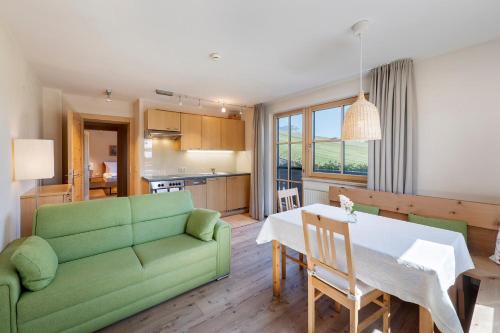 ein Wohnzimmer mit einem grünen Sofa und einem Tisch in der Unterkunft Gästehaus Bramböck in Bad Häring