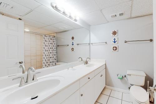 a white bathroom with two sinks and a toilet at Long Beach Resort #T2-304 in Panama City Beach