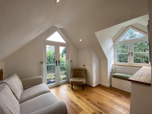 a living room with a couch and two windows at Candlewick Cottage in Steeple Aston