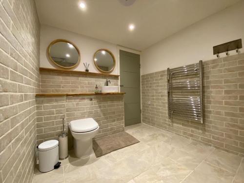 a bathroom with a toilet and two mirrors on the wall at Candlewick Cottage in Steeple Aston