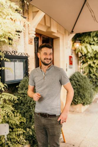 a man standing in front of a building at Hôtel Le Cro-Magnon in Les Eyzies-de-Tayac