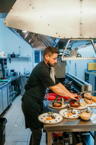 a man preparing food on a table in a kitchen at Hôtel Le Cro-Magnon in Les Eyzies-de-Tayac