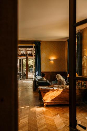 two people sitting in a room with a wooden table at Hôtel Le Cro-Magnon in Les Eyzies-de-Tayac