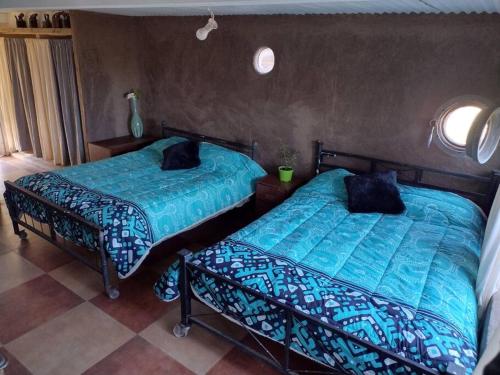 two beds sitting next to each other in a bedroom at La casa de Barro Primer piso in Pichidangui