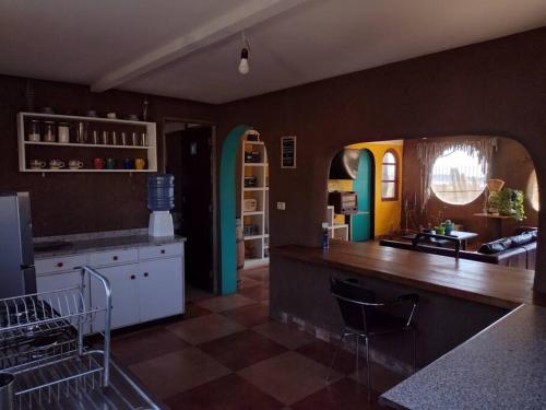 a kitchen with a table and a counter with chairs at La casa de Barro Primer piso in Pichidangui