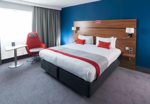 ein Hotelzimmer mit einem großen Bett und einem roten Stuhl in der Unterkunft Holiday Inn Express Birmingham Star City, an IHG Hotel in Birmingham
