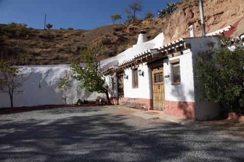 a small white building with a door on a street at Casas Cueva y Cortijo La Tala en Guadix in Guadix
