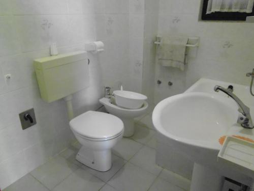a white bathroom with a toilet and a sink at Apartments Krešimir beauty with shadow trees and parking place in Pag