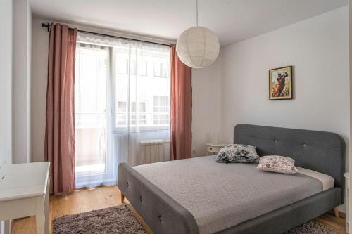 a bedroom with a bed and a large window at Designed Apartment in Central Sofia in Sofia