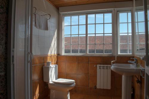 baño con aseo y lavabo y ventana en Hostal Galicia, en Monforte de Lemos