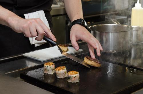 a person is preparing food in a kitchen at Hotel Restaurant Spa Ivan Vautier in Caen