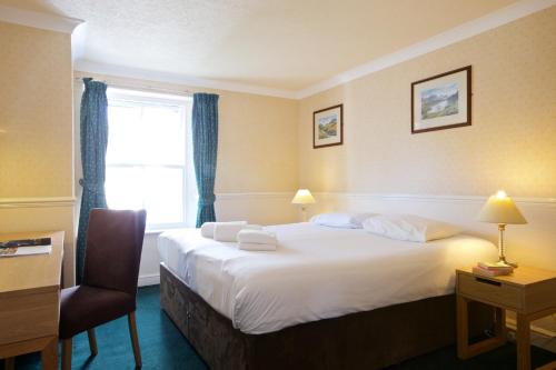 a hotel room with a bed and a chair and a window at The Derwentwater Hotel in Keswick