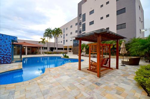 a swimming pool with a gazebo next to a building at Business Park Hotel in Hortolândia