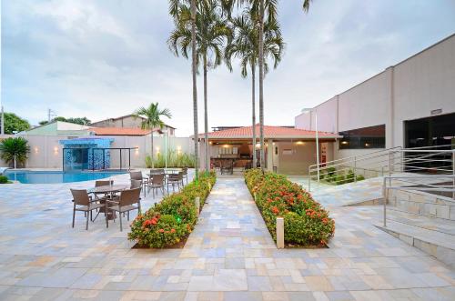 a patio with tables and chairs and palm trees at Business Park Hotel in Hortolândia