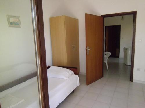 a bedroom with a bed and a wooden cabinet at Apartments Krešimir beauty with shadow trees and parking place in Pag