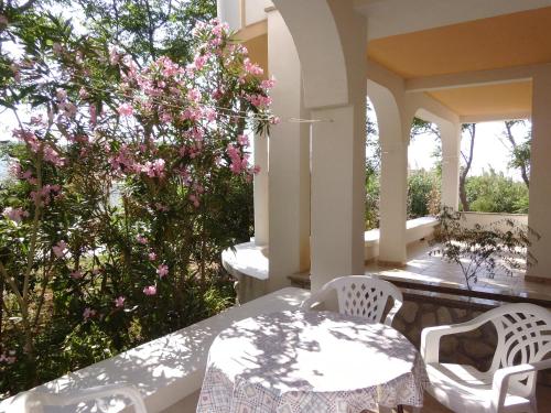 una mesa con sillas y un árbol con flores rosas en Apartments Krešimir beauty with shadow trees and parking place, en Pag